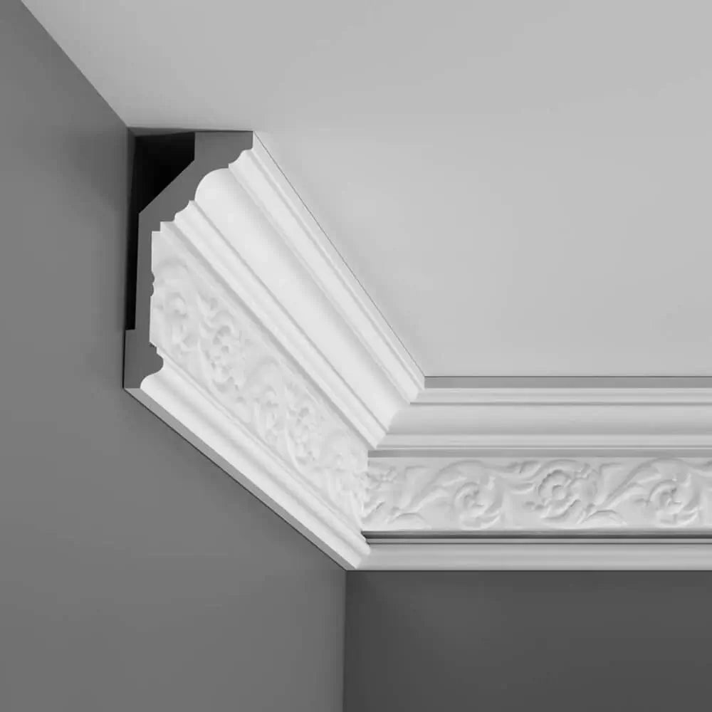 Die dekorative weiße Stuckleiste von Orac Decor mit einem aufwendigen Blumen- und Blattmuster wertet die graue Wand wunderschön auf und umrahmt elegant die Ecke, wo Wand und Decke aufeinandertreffen. Diese aus Purotouch gefertigte Zierleiste verleiht dem Raum eine anspruchsvolle und stilvolle Note.